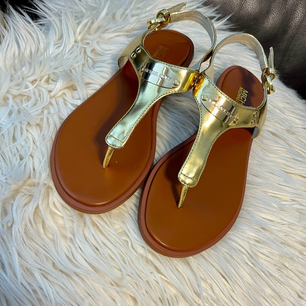 A gold pair of Michael Kors Sandals, Size 7